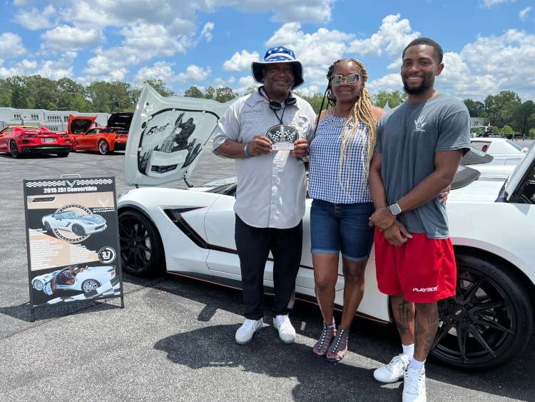 Three people are holding a trophy at a car show in Georgia.
