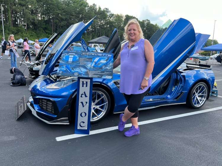A woman is standing beside a custom C7 Corvette