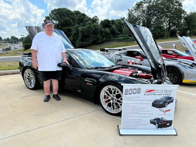 A man standing beside a 2008 Corvette coupe