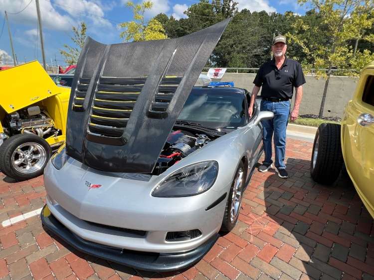 A person is standing beside a C6 Corvette coupe