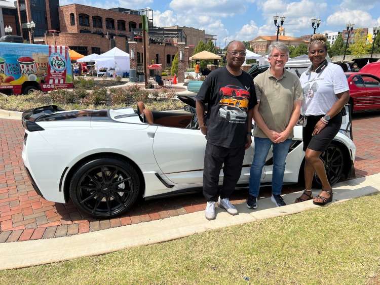 People standing around a C7 Corvette convertible.