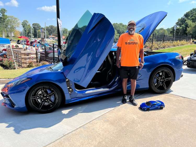 A man standing beside a C8 Corvette coupe.
