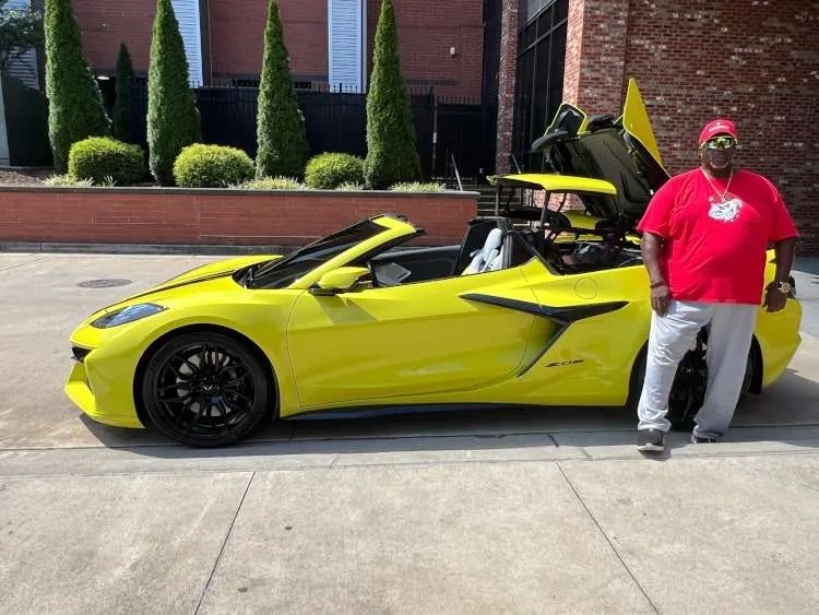A man standing beside a yellow Z06 Corvette..
