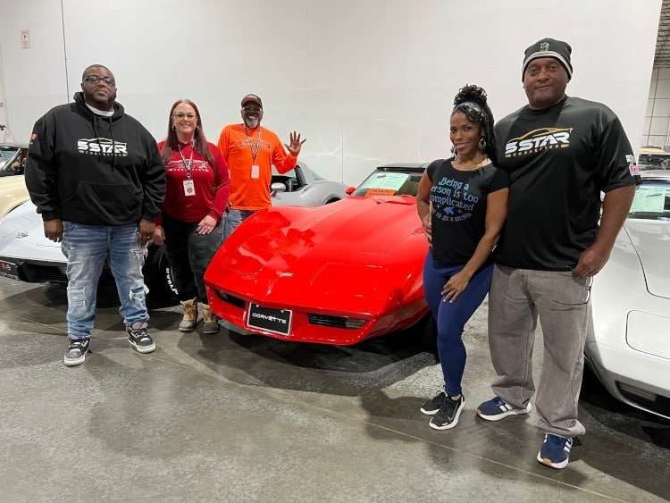 People standing around a Corvette