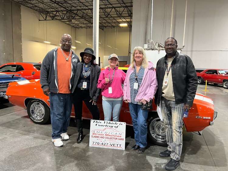 People standing around a Camaro.