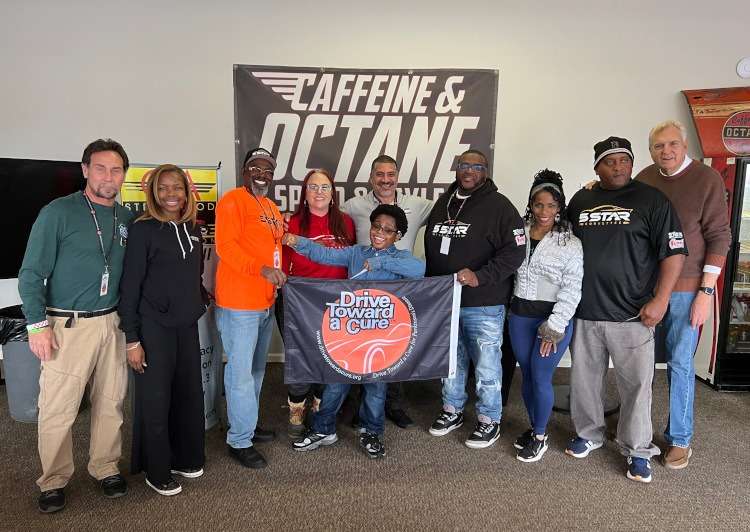 A group of people indoors holding a banner.