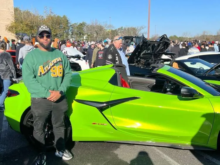A man standing beside a green Corvette