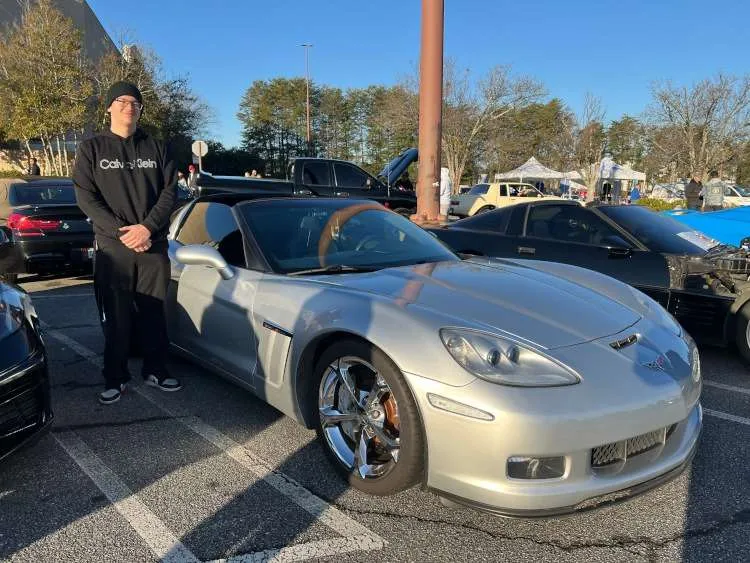 A man standing beside a 2013 Corvette coupe