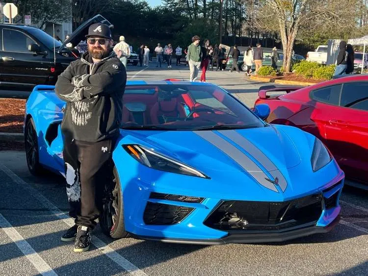 A man is standing beside a C8 Corvette coupe