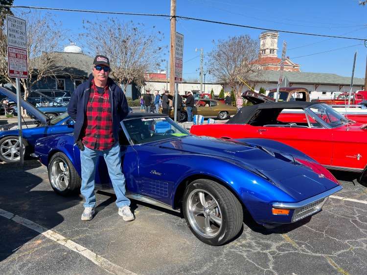 A man standing beside a blue Corvette