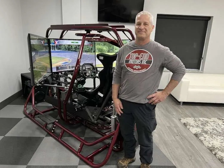 A man standing beside a sim-craft simulator