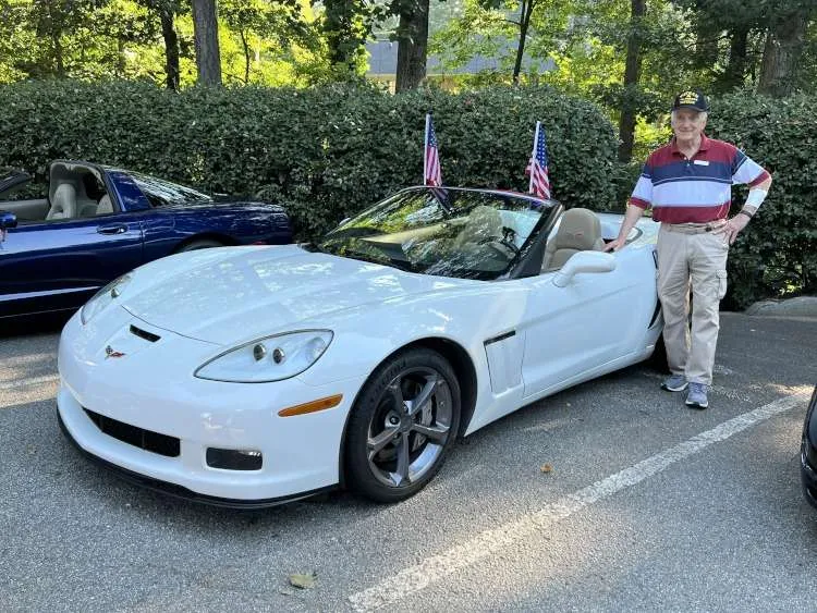 Man stands beside a sixth-generation Corvette.
