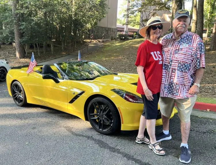A couple stands beside their C7 Corvette.