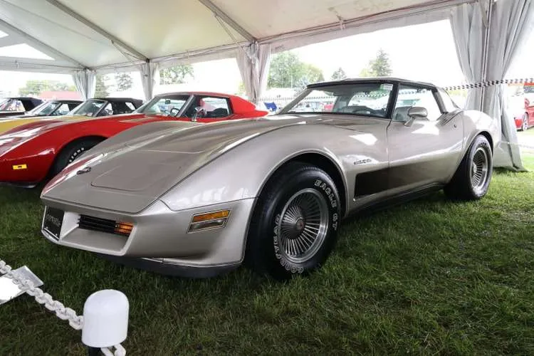A beige 1982 Corvette with cross-fire injection and turbine wheels, displayed under a white tent with other classic Corvettes in the background at the Corvettes at Carlisle 2025 event. Photo from Vettes of Atlanta Magazine.