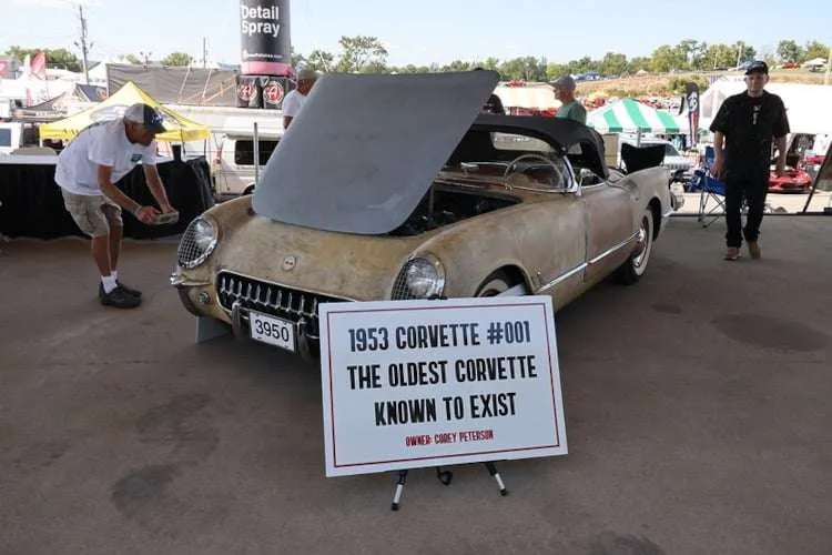 The oldest known surviving Corvette, a restored 1953 model with the serial number '001', on display at Corvettes at Carlisle 2025 with its hood open and a sign identifying it as the "oldest Corvette known to exist. Photo from Vettes of Atlanta Magazine.