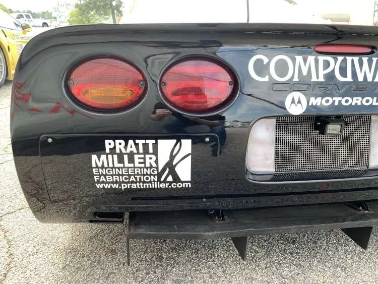 Close-up of the rear bumper of a Corvette race car, showing the Pratt & Miller Engineering Fabrication decal alongside Compuware and Motorola sponsorships. The image features the iconic Corvette round tail lights and a racing diffuser.