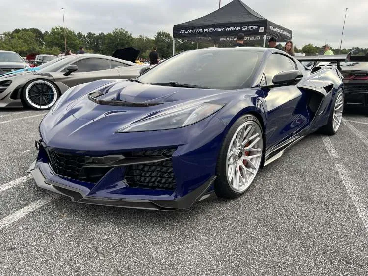Three-quarter front view of a 2025 Corvette ZR1 in Hysteria Purple Metallic with high-gloss carbon fiber aero, silver forged wheels, and orange brake calipers.