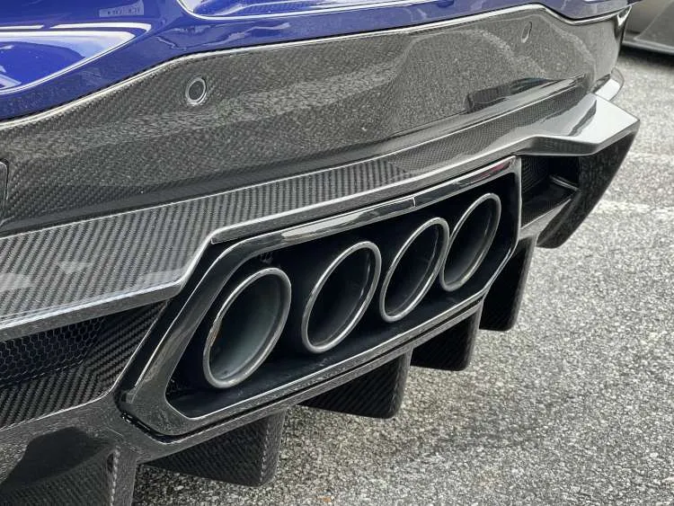 Close-up of the center-mounted quad exhaust system on a Hysteria Purple 2025 Corvette ZR1, surrounded by a high-gloss carbon fiber rear diffuser and aerodynamic strakes.
