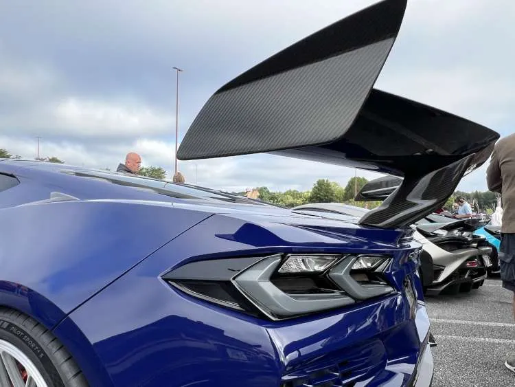 Close-up rear angle of a blue 2025 Corvette ZR1 featuring a massive carbon fiber high-wing spoiler and modern LED taillight assembly.