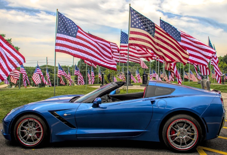 Blue C7 Stingray Corvette with American flags in the background