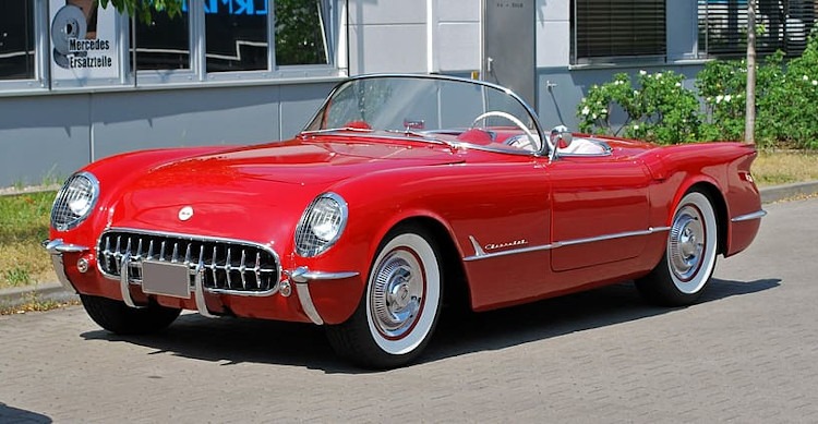 Red convertible first generation Corvette with white interior and wide white sidewall tires