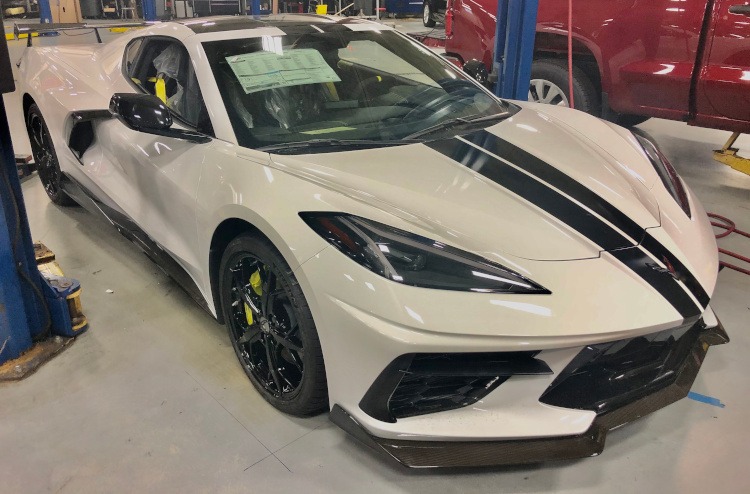 Dealer prepping a white C8 with black racing stripe