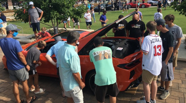 Crowd of people around a Sebring Orange C8 Corvette