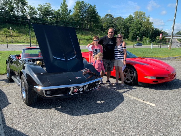Family beside a 1969 Corvette and a 2002 Corvette convertible
