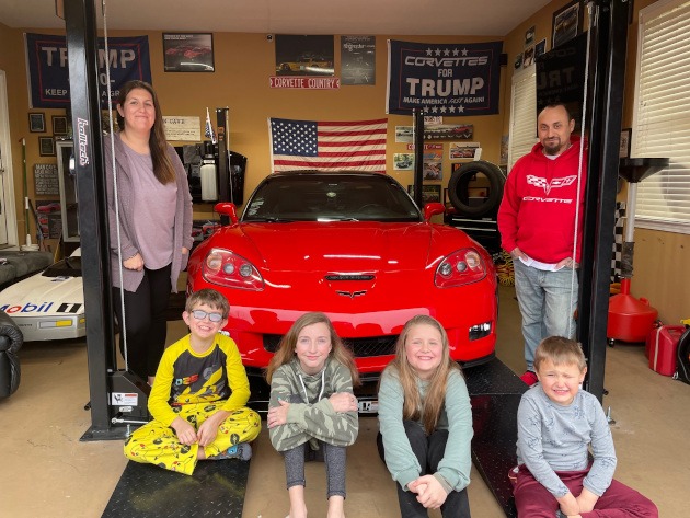 Family in a garage with a sixth-generation Corvette