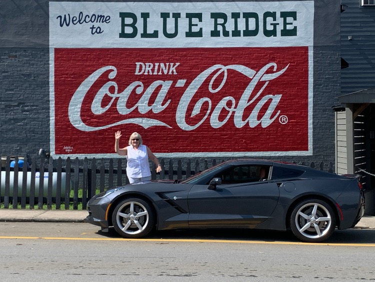 Seventh-generation 2014 Corvette beside a Coca=Cola mural