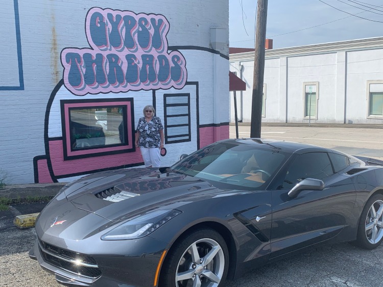 Seventh-generation Corvette beside wall mural of Gypsy Threads