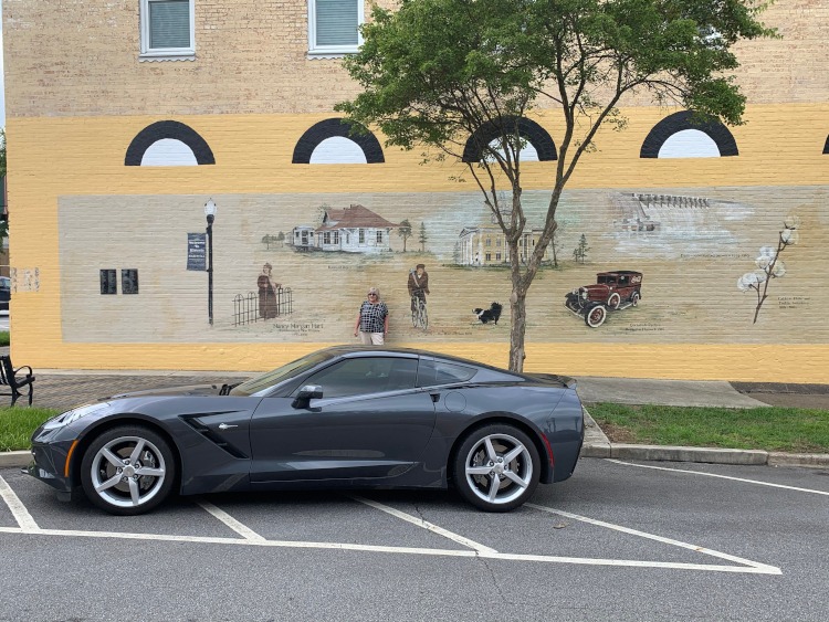 Seven-generation Corvette parked by building mural in Hartwell, Ga.