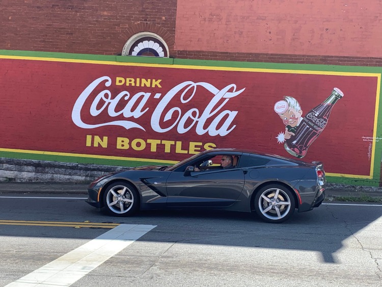 Seventh-generation Corvette parked beside a Coca-Cola building mural