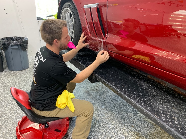 Installing XPEL paint protection film to a red Corvette rocker panel