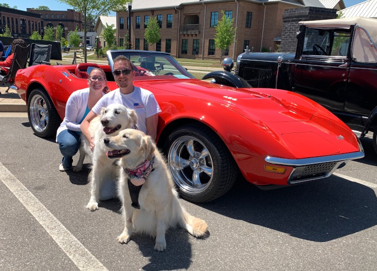 Young couple with two dogs beside their 1970 red Corvette