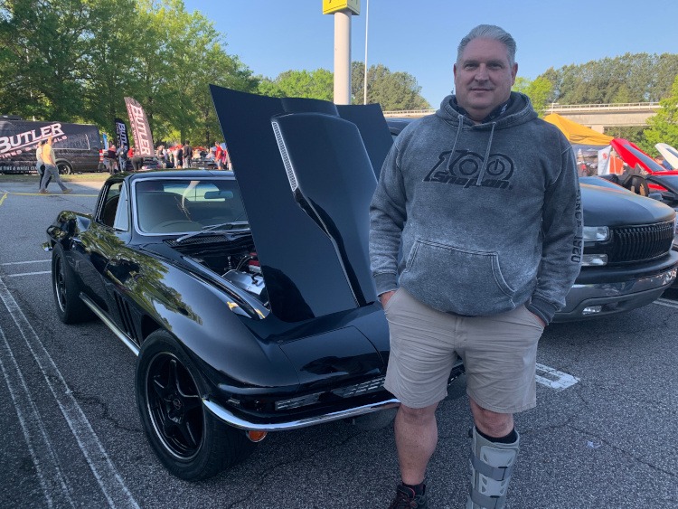 Second-generation black Corvette coupe with owner standing beside