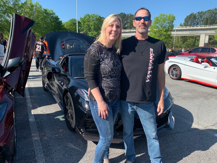 Eighth-generation black Corvette coupe with a couple standing beside it