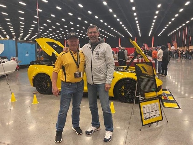 Two guys standing in front of a yellow Corvette
