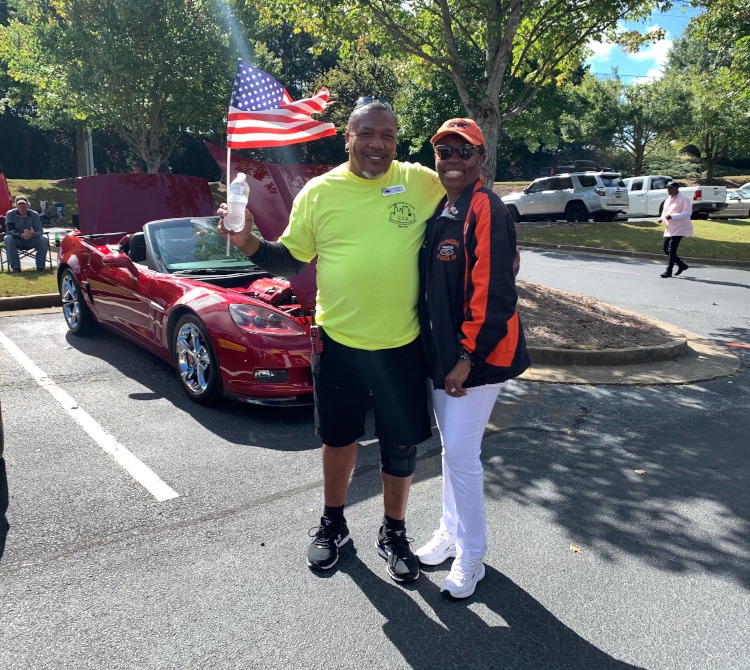 Two people holding and waving a flag at a Corvette car show