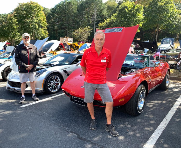 Two people and their Corvettes at a car show