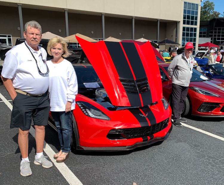 Owners standing by their Corvettes at a car show