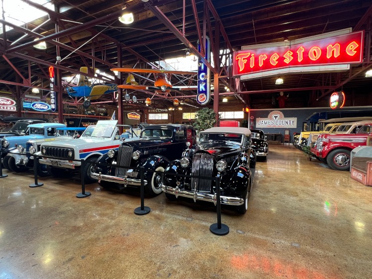 Classic cars with planes hanging from the ceiling with a neon Firestone sign