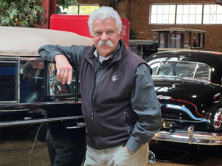 Owner of the Coker Museum beside a black car