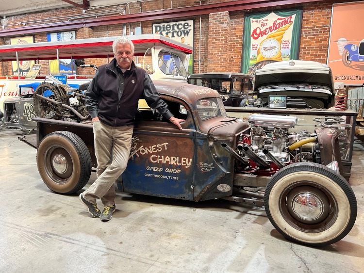 Corky Coker in front of a vintage hot rod from Honest Charley's Speed Shop