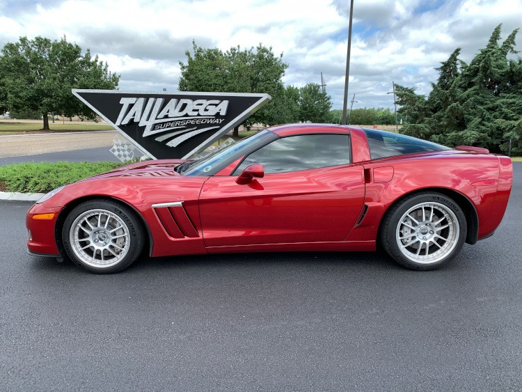 Crystal Red Corvette coupe parked beside Talladega Speedway sign