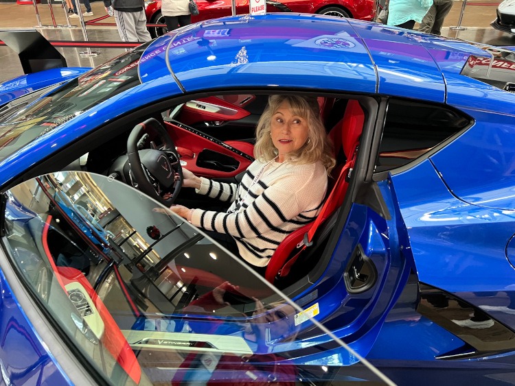 A woman sitting in an Elkhart Lake Blue Corvette coupe