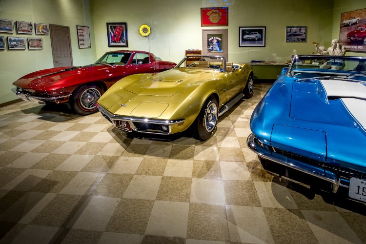 3 vintage corvettes in a dealership scene at the NCM