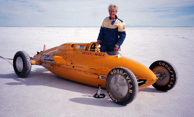 Geri Kelly standing besider her orange racecar