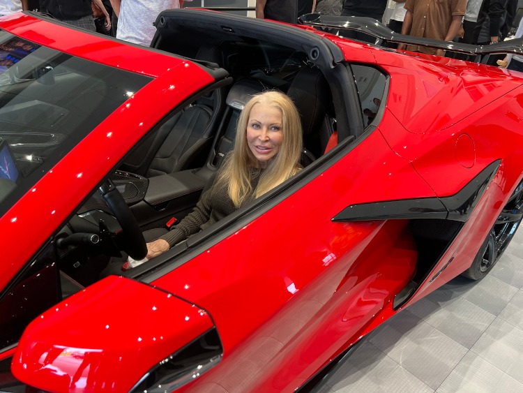 A lady sitting in an eighth-generation Torch Red Z06 edition Corvette