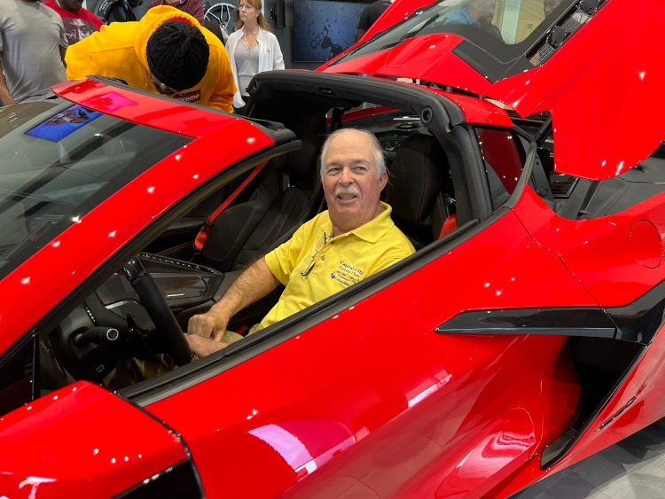 A man sitting in an eighth-generation Torch Red Z06 Corvette coupe